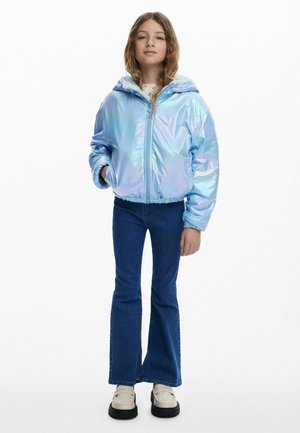 Iridescent blaue Daunenjacke mit Kapuze, ausgestattet mit elastischen Bündchen und Saum, kombiniert mit ausgestellten Denim-Jeans und weißen Schuhen.