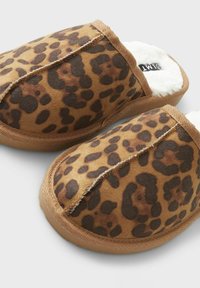 Leopardimustriga sussid pehme ja plüüsist sisuga, ümmarguse kujuga ja pruunist nahast välispinnaga. Omab beeži õmblust ja kummist tallat.