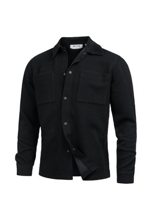 Black quilted long-sleeve shirt jacket with collar, snap buttons, and two chest pockets, shown partially unbuttoned.