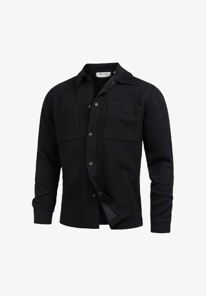 Black quilted long-sleeve shirt jacket with collar, snap buttons, and two chest pockets, shown partially unbuttoned.