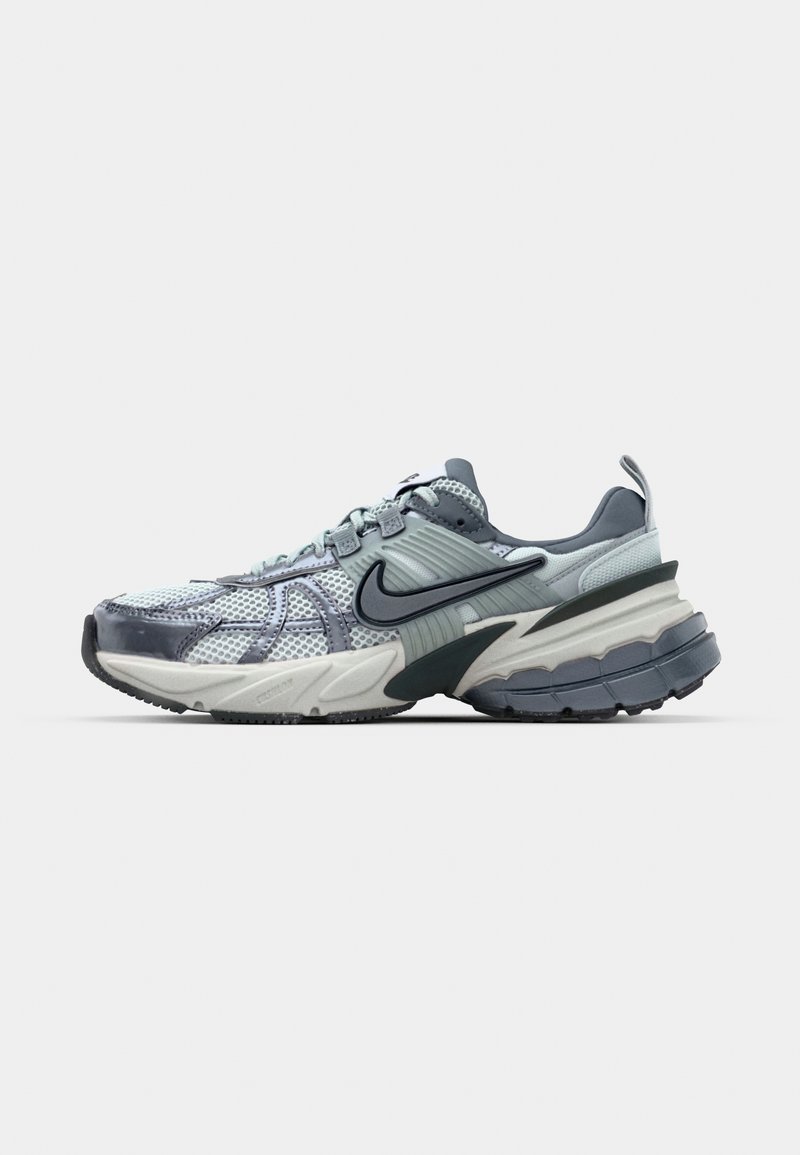 Zapatillas Nike con parte superior de malla en gris claro y azul, suela gruesa y acolchada con un diseño en capas, logo Swoosh en negro contrastante.