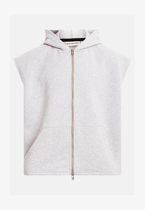 Lysegrå, ærmeløs hættetrøje med lynlås foran og kengurulomme, mærket "Redefined Rebel" indeni kraven.