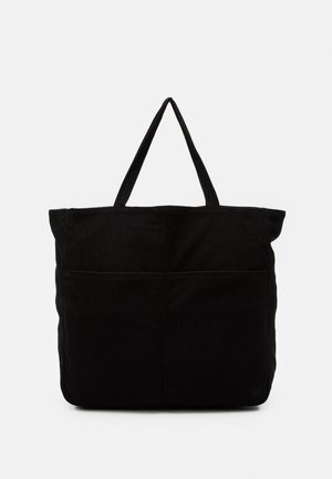 Sac en velours côtelé noir avec deux poignées courtes, arborant un design cousu et une poche avant pour le rangement.