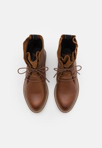 Brune lærstøvler med en blød suede krave, rund tå og tekstureret overflade. Har snørebånd og en kontrasterende lys søm detalje.