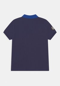 Námořnická modrá polo košile s kontrastním modrým límečkem, krátkým rukávem a detailem loga na levém rukávu. Hladká textura, neformální design.