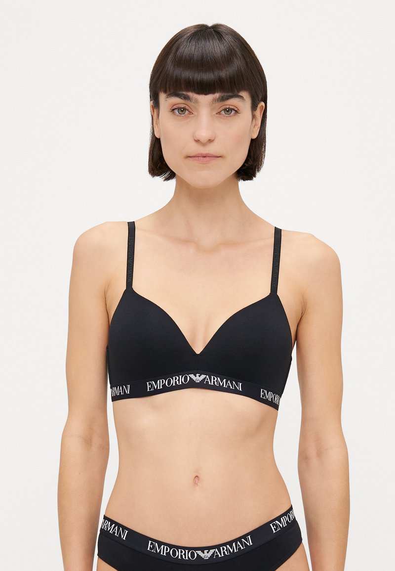 Melna bezvadu krūšturis ar gludu tekstūru, aprīkots ar regulējamiem siksnām un zīmolu elastīgu joslu ar "Emporio Armani" logotipu.