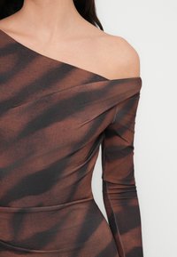 Καφέ και μαύρο φόρεμα με σχέδιο χωρίς ώμους και μακριά μανίκια. Το ύφασμα έχει λείο υφή με ελαφριά πτύχωση και λεπτομέρεια με ρέλιασμα.