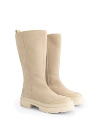 Hoge beige suède laarzen met dikke, robuuste crèmekleurige rubberen zolen, ronde neuzen en trekbanden aan de achterkant, weergegeven op een witte achtergrond.