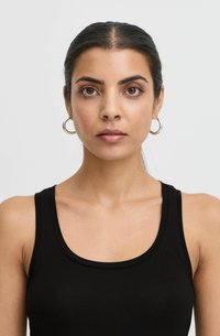 Čierna bezrukávová tank top s okrúhlym výstrihom, hladkou textúrou a priliehavým strihom. Na modeli sú malé zlaté kruhové náušnice.