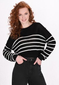 Zwart-wit gestreepte gebreide trui met een ronde halslijn en een gestructureerde stof, gecombineerd met hoge zwarte jeans.