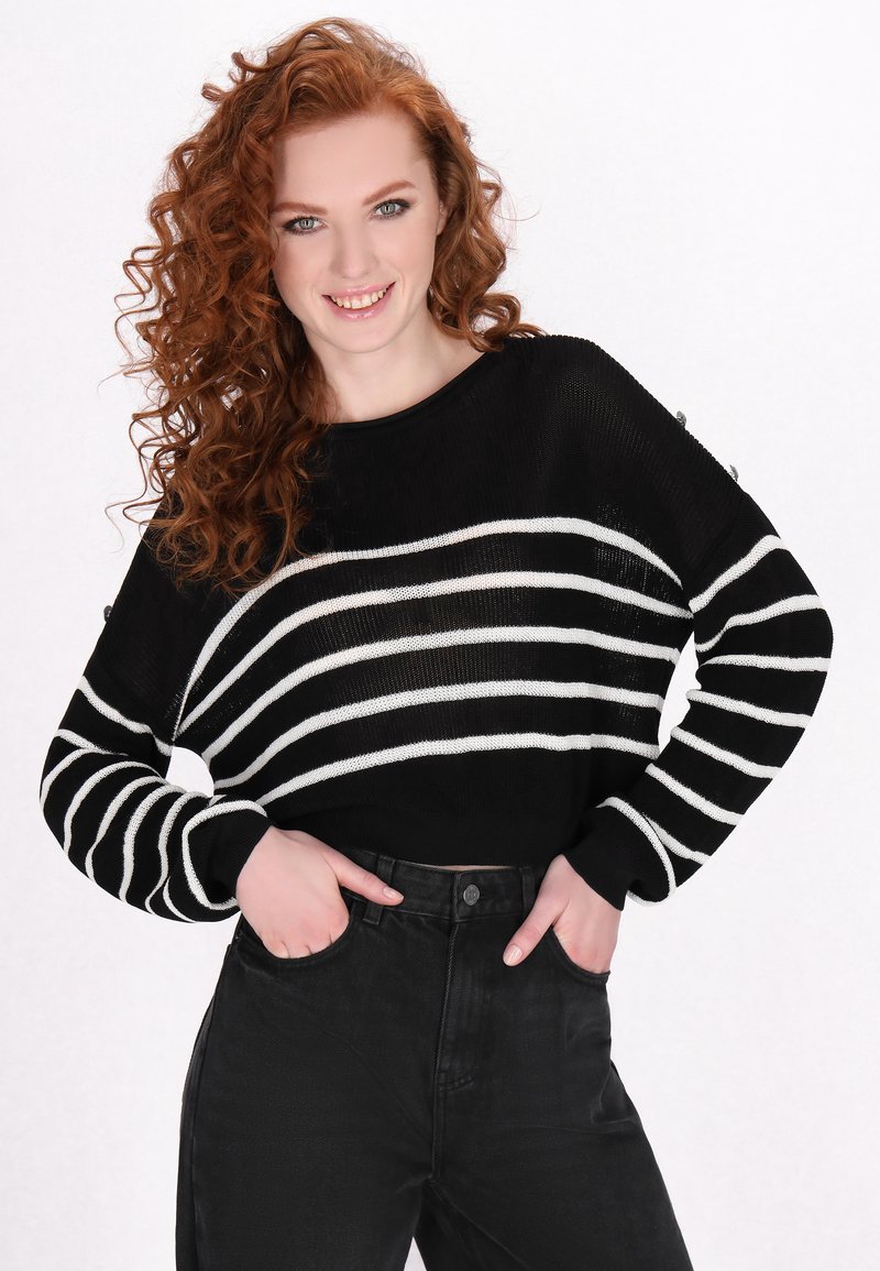 Zwart-wit gestreepte gebreide trui met een ronde halslijn en een gestructureerde stof, gecombineerd met hoge zwarte jeans.