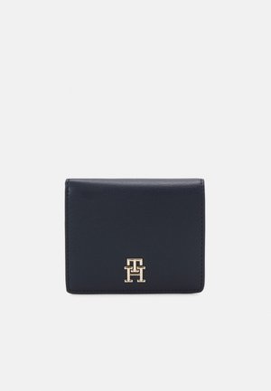 Navy blue leather wallet with a compact, rectangular shape. Features a gold logo accent on the front. Smooth texture, minimal design.
