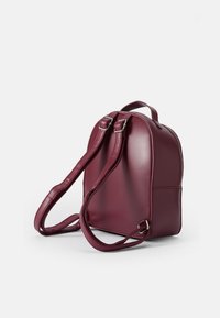 Sac à dos en simili cuir bourgogne avec une forme arrondie, une seule poignée supérieure, des bretelles ajustables et des détails en zip argenté.