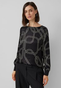 Schwarze Bluse mit einem fließenden Design, das weiße abstrakte Linien zeigt. Lange Ärmel mit enganliegenden Manschetten. Glatte, glänzende Textur.