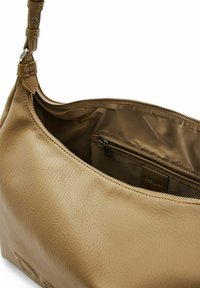 Sac à main en cuir fauve avec une surface douce et texturée, fermeture éclair, et un intérieur lisse comprenant une petite poche zippée et une étiquette de marque.