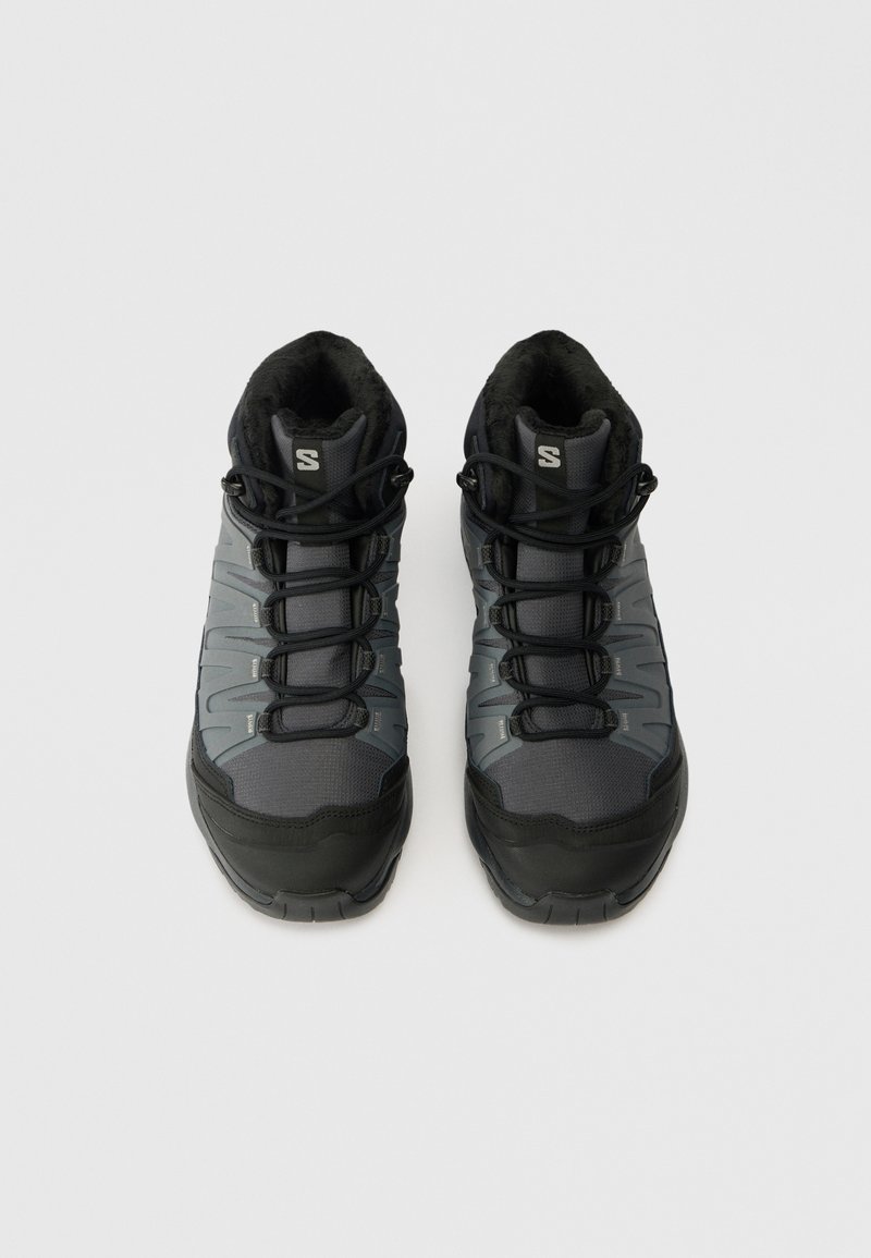 Ein Paar schwarze und graue Schnürwanderschuhe mit gepolstertem Schaft und weicher Innenauskleidung, von oben auf einem weißen Hintergrund betrachtet.