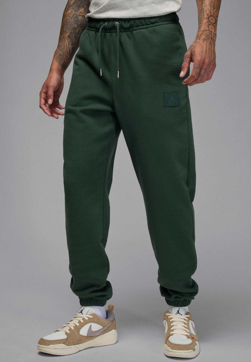 Pantaloni della tuta in cotone verde con vita e polsini elasticizzati, con una piccola toppa logo sulla coscia sinistra e vestibilità comoda.