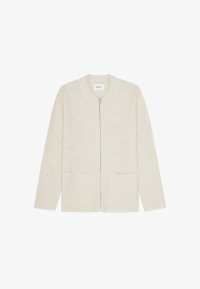 Giacca zip-up beige chiaro con colletto, due tasche frontali e un tessuto morbido e testurizzato. Design minimalista senza motivi visibili.