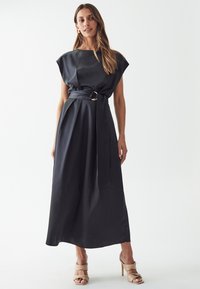 Black, satin, cap-sleeved maxi dress with a belted waist featuring a gold circular buckle. Smooth texture, flowing silhouette.