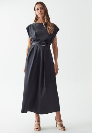 Black, satin, cap-sleeved maxi dress with a belted waist featuring a gold circular buckle. Smooth texture, flowing silhouette.