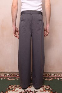 Šedé široké nohavice s hladkým povrchom, so plochým pásom, dvoma zadnými vreckami a prispôsobeným strihom, umiestnené na neutrálne pozadí.