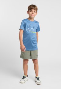 Light blue t-shirt featuring a graphic of two characters and text "OUT AND PLAY". Paired with olive green shorts and white sneakers.