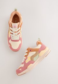 Baskets multicolores avec un mélange de matériaux rose, crème, vert et orange. Présentent une surface texturée, des lacets blancs et une étiquette de logo.