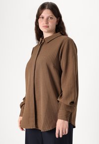 Brown striped button-up shirt with a collar, featuring long sleeves and a relaxed fit. Subtle white pinstripes and soft fabric texture.