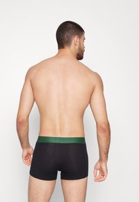Zwarte boxershorts met een groene tailleband, gemaakt van een gladde stof. Het ontwerp heeft een snug fit en een mid-rise snit.