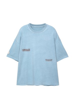 Hellblaues, übergroßes T-Shirt aus weichem Stoff. Mit kontrastierendem Druck "KOPENHAGEN" und "KREATIVES STUDIOAUSSTELLUNG".