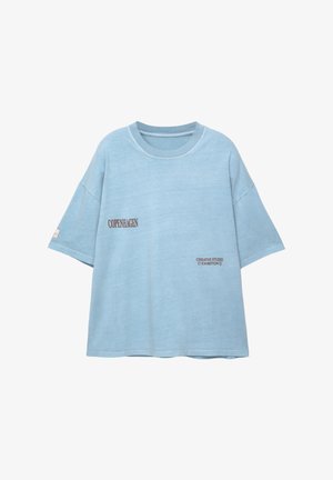 Hellblaues, übergroßes T-Shirt aus weichem Stoff. Mit kontrastierendem Druck "KOPENHAGEN" und "KREATIVES STUDIOAUSSTELLUNG".