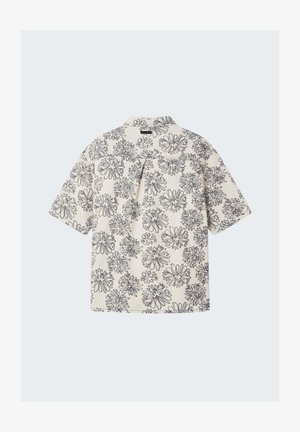Short-sleeve cream shirt with black abstract floral patterns, single pleat below the yoke, and a folded collar.