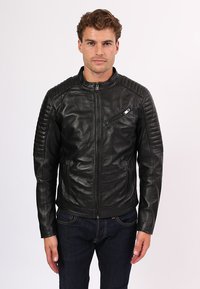 Giacca da moto nera in pelle con accenti trapuntati sulle spalle, chiusura anteriore con zip, due tasche laterali e una tasca sul petto con zip.