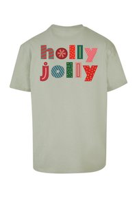 Hellgrünes T-Shirt mit dem Text "holly jolly" in verschiedenen Mustern und Farben: rot, grün, blau und pink mit Akzenten wie Punkten und Streifen.
