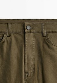 Ceinture de pantalon vert olive avec bouton supérieur, passants de ceinture, poches avant et détails de double surpiqûre visibles.
