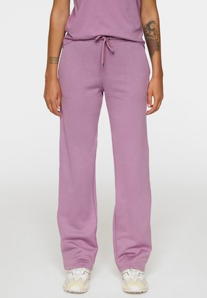 Lila sweatpants met een trekkoord tailleband, relaxte pasvorm en zachte textuur, gecombineerd met wit en beige patroon sneakers.