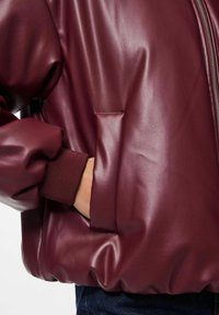 Burgundy imitation läderjacka med en figurnära silhuett, ribbade ärmslut och en sidoficka, som visar en jämn textur och subtil lyster.