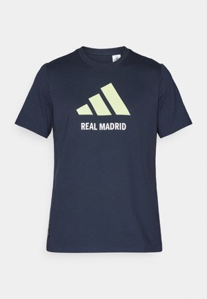 T-shirt in cotone blu navy con un grande logo Adidas di colore verde chiaro e la scritta "REAL MADRID" in bianco. Maniche corte, design classico con collo a giro.