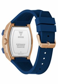 Blå silikonarmband som ansluter till ett fyrkantigt klockhus av rostfritt stål med roséguldfinish, som visar varumärke och vattentåliga detaljer på baksidan.