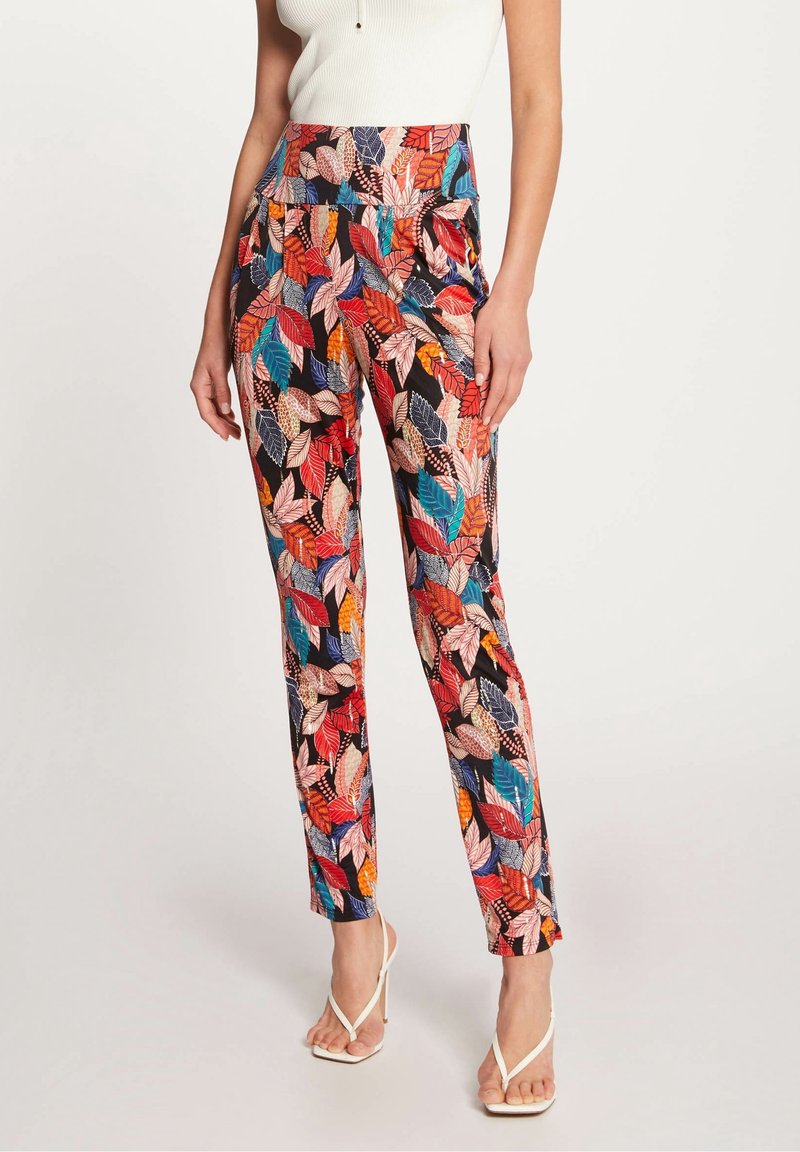 Pantalons à motifs arborant un imprimé de feuilles vibrant dans des teintes de rouge, bleu et orange sur fond noir. Design taille haute avec une finition lisse.