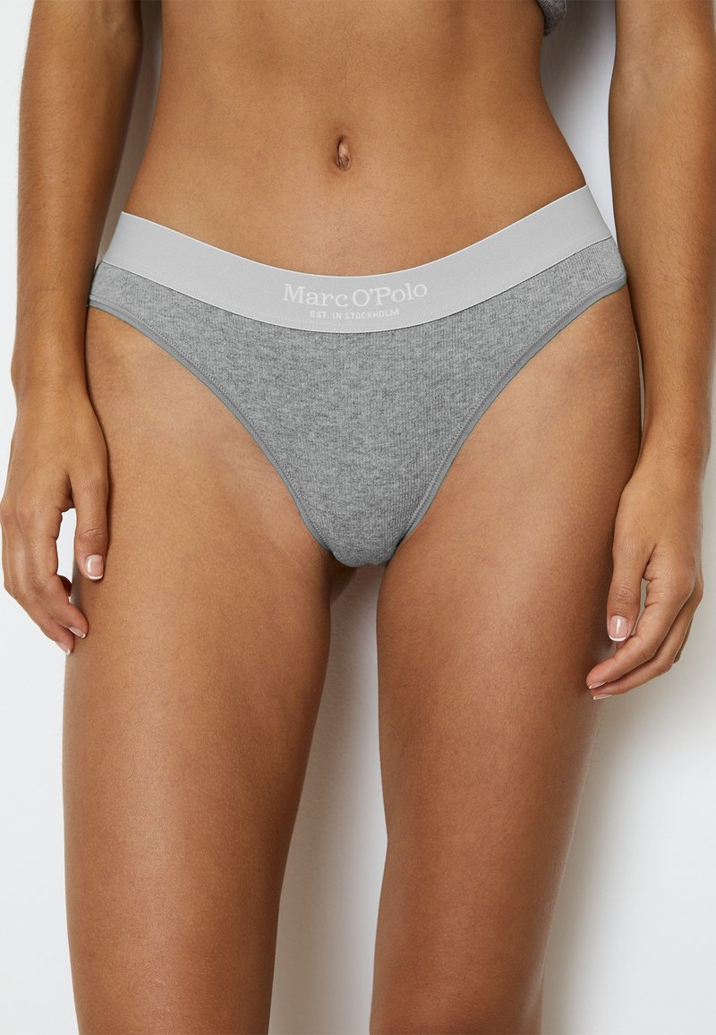 String gris en coton avec une bande élastique douce. La bande élastique présente le logo "Marc O’Polo". Texture lisse, design minimaliste.