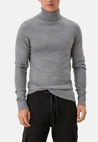 Pull à col roulé gris en tissu doux, coupe ajustée, avec manches longues et col côtelé, associé à un pantalon noir à cordon de serrage.