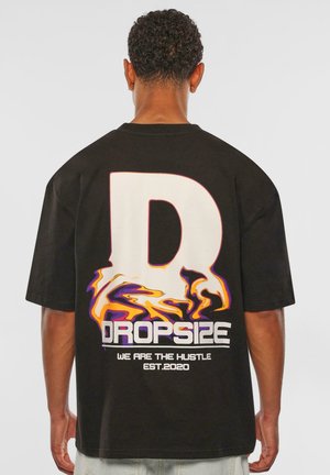 Sort t-shirt med korte ærmer, der har et stort hvidt bogstav "D" og farverige flammegrafikker med teksten "DROPSIZE VI ER HUSTLEN EST.2020."