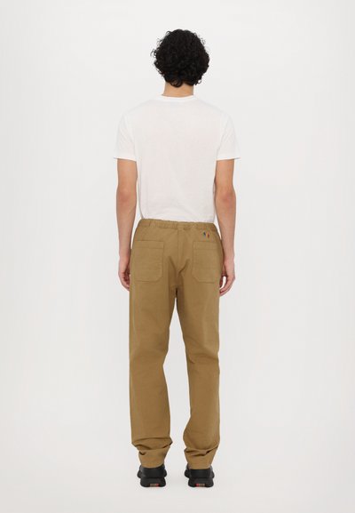 Khaki pants with a relaxed fit, elastic waistband, two back pockets, and multicolor stitching accents. Worn with a plain white t-shirt.