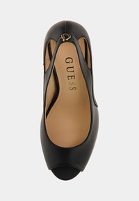 Svarta lädersandaler med öppen tå, utskurna sidor och guldspänne, beige innersula stämplad med "GUESS"-logotyp.