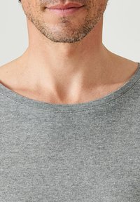 T-shirt in cotone grigio con scollatura ampia, caratterizzato da una texture liscia e maniche corte, che sottolinea un design minimalista.