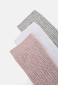 Three pairs of ribbed cotton socks: pink, white, and gray. Each has a textured knit design, with a soft, stretchy fit at the top.
