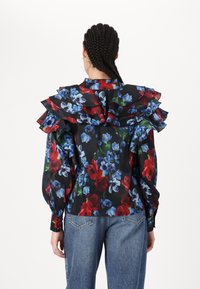 Floral blouse with ruffled collar, featuring red and blue flowers on a black background. Long sleeves with gathered cuffs, sheer fabric texture.