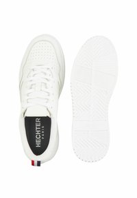 Weiße Sportschuhe mit perforiertem Obermaterial, flachen Schnürsenkeln und Logo auf der Zunge. Strukturierte Gummisohle mit Fischgrätmuster.