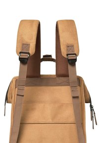 Sac à dos en toile marron avec des bretelles rembourrées réglables, équipé d'une poignée supérieure et d'une poche zippée à l'avant. Matériau durable et design pratique.
